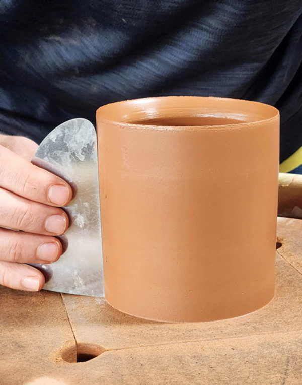 1 Smooth the outside of the mug with a flat-edge metal rib.