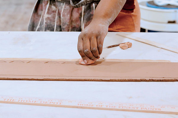 1 Roll out a slab in excess of 30 inches in length and 4 inches in height. Compress the slab with a rubber and/or metal rib, then stamp with a bisque-fired stamp in a repeating pattern. 