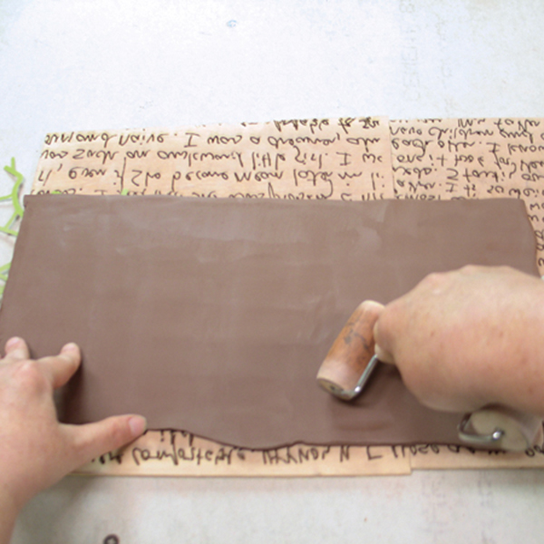 3 Press the slab of clay into the stamp using a pony roller.