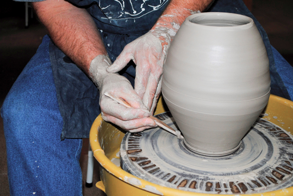 3 Using a wooden knife, trim excess clay from the base, create a bevel for visual lift, and make a mark around the widest part of the form to guide later alterations.