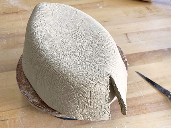 5 Drape the lace-textured slab over the oval plaster mold and dart it to fit.