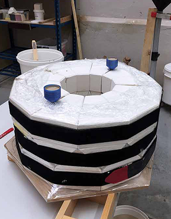 14 The mold is now complete and filled with clay slip through the black funnel and the hose attached to the bottom of the mold. The blue funnels allow the air to go out and back in during the draining of the mold. 