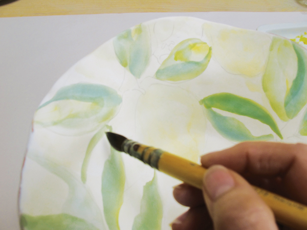 4 Start painting the leaves, mixing stain colors on the plate and double loading the brush with greens and yellows.