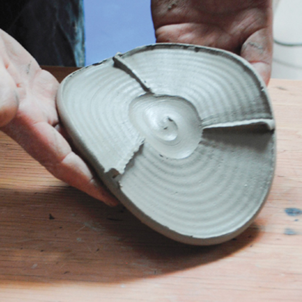 7 Start the spout with a thrown clay disk with a recessed center, then make shallow cuts into the outer area of the disk to create textures and raised lines that divide the circle into three sections.