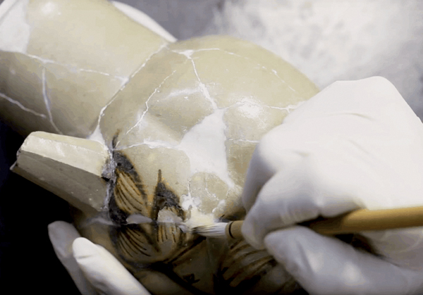 A technician colors a broken antique porcelain piece during restoration. Researchers in Germany explored the potential of using additive manufacturing techniques to restore historical ceramics. Credit: New China TV, YouTube.