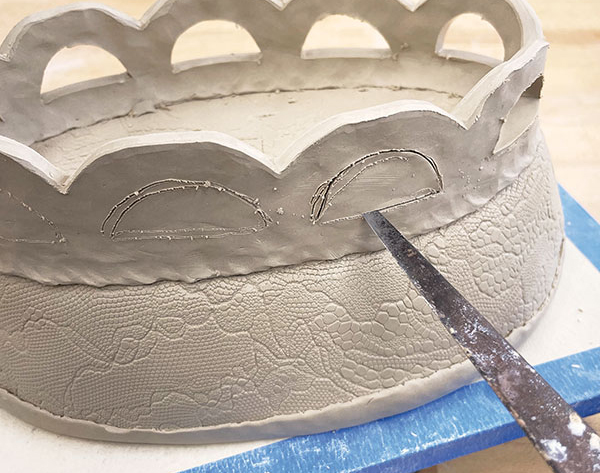 9 Cut out half circles under each of the scallops to add interest to the foot. Leave the piece upside down until it is leather hard. 