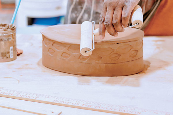 8 Add slip to the scored edge of the cut slab, flip over the body of the dish and score alongside the bottom edge, then attach the two pieces together. Use a pony roller to compress the bottom slab to the body of the dish. 
