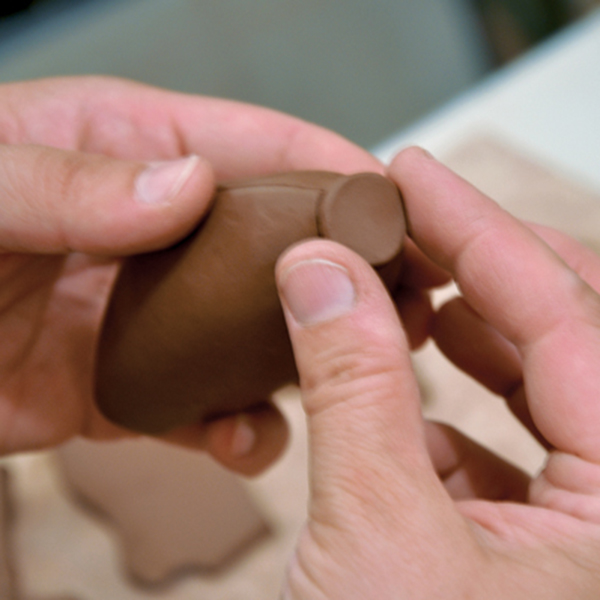 5 Attach a small, flat clay disk to the end of the handle where the metal utensil will connect to it.