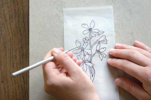 Punching holes through tracing paper to create an image transfer.