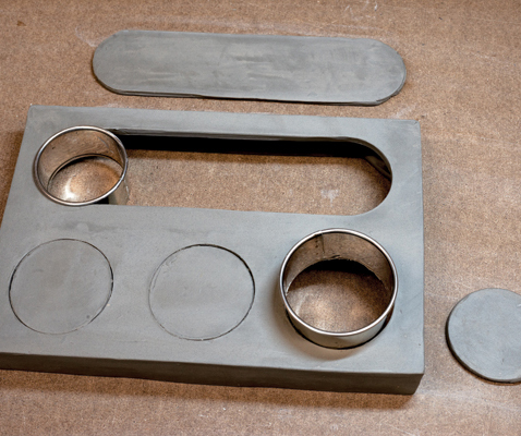 10 Use two different sizes of metal circle cutters to make the three holes for the boxes and the long tray compartment.