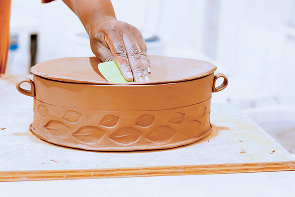 10 Cut and generously measure a soft slab for the lid. Drape the soft slab over the leather-hard casserole dish and use a rubber rib to press down on the slab, creating a curve. This slab will be flipped over when the clay reaches the leather-hard stage to become a lifted, domed lid. Cut out and refine the leather-hard lid.