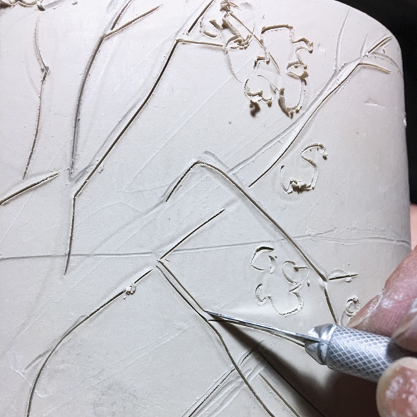 10 Incise the lines of the drawings into the leather-hard clay using an X-Acto blade. Make sure to pull the blade to slice into the clay, rather than pushing it or dragging it sideways.