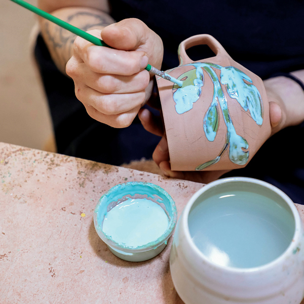 K Apply wax resist over the underglaze surface design on the bisque-fired mug.