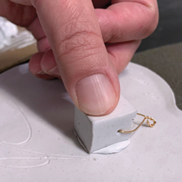 13 Using epoxy, attach a fired ceramic cube fitted with a loop of hanging wire near the top of the back of the tile. 