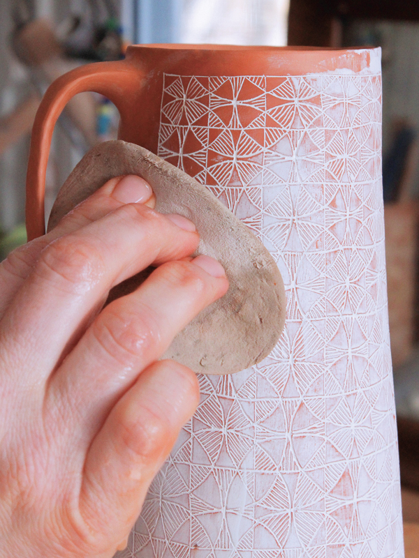 20 Use a damp sponge to remove additional underglaze from the clay surface. Continue this until you expose the entire carved pattern underneath. 