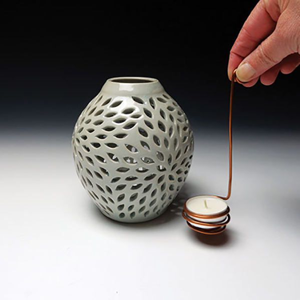 Pierced vase, 6¼ in. (16 cm) in height, wheel-thrown and pierced white stoneware, glaze, fired to cone 7 in reduction, copper wire tealight cradle, 2020.