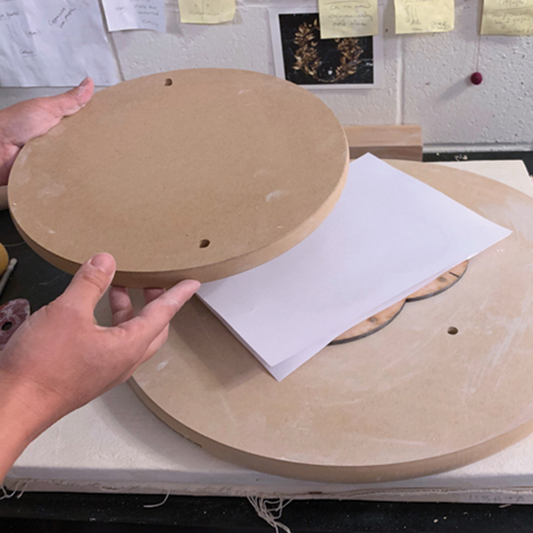 6 Put a second sheet of paper and a flat board on top of the slab, then flip it over.