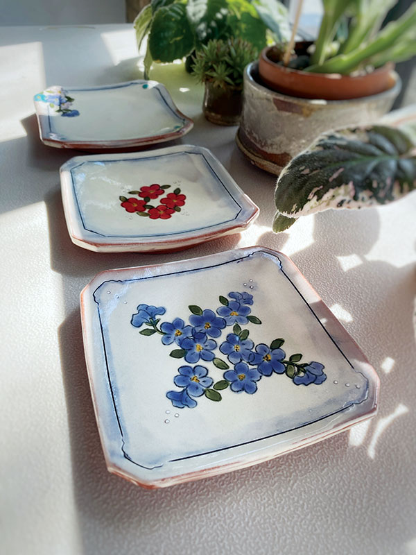 Jenn Cole’s dessert plates, 4½  in. (11 cm) in length (each), wheel-thrown and altered earthenware, white slip, hand-painted underglaze, cobalt wash, clear glaze, fired to cone 04 in an electric kiln.