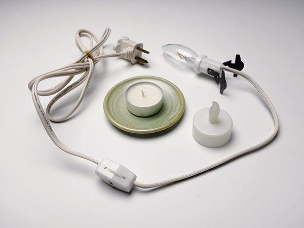 A Light sources: wax-candle tealight, LED tealight, and candelabra bulb screwed into an electrical cord with an in-line switch and a clip-in socket. 