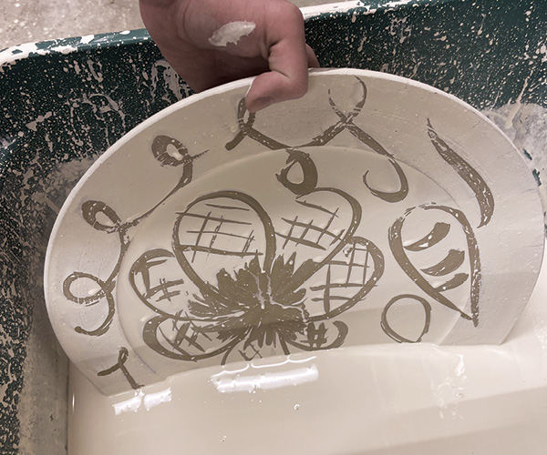 12 Once the wax has dried, dip the platter into slip.