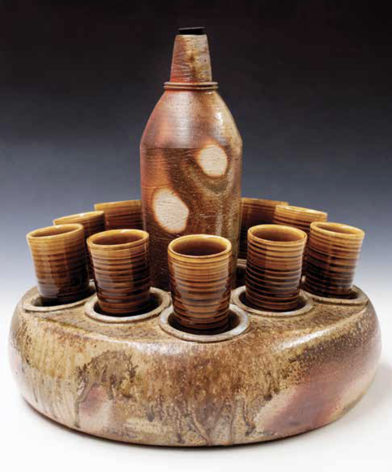3 Bourbon cups and bottle caddy set, to 16 in. (41 cm) in height, wheel-thrown stoneware with flashing slip (bottle and caddy), wood fired in an anagama kiln, porcelain with glaze (cups), fired in reduction, 2015.