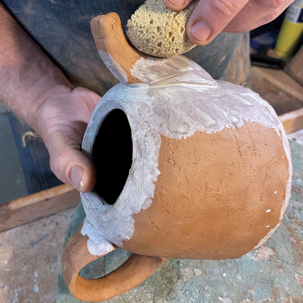 1 Add a few layers of terra sigillata to the bone-dry teapot with a sponge. 