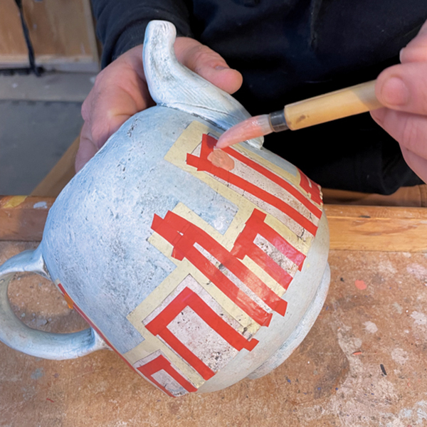5 Use automotive pinstripe tape to block off spaces where you want to add underglaze, then paint on the underglaze. 