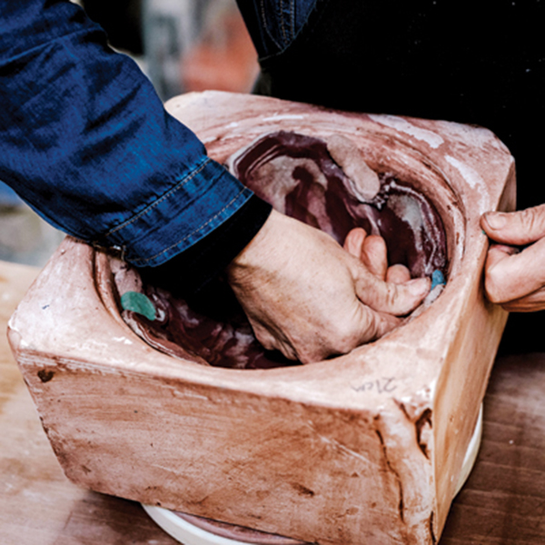 9 Adding a layer of colored clay and found materials to the black-and-white marbled walls in the mold. 