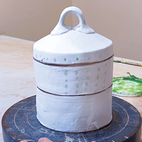 12 Dip the jar in white slip. Use wax resist to paint a pattern over the slip on the jar.