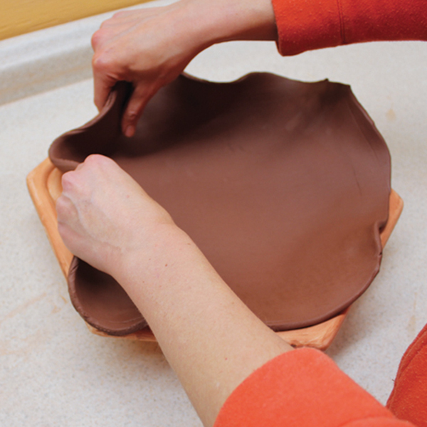 4 Drape a compressed slab over the mold and gently fit it into the corners, making sure it is an even thickness all around.