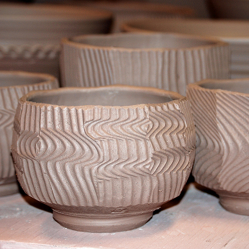 8 After the pot reaches leather hard, slightly bevel the rim edge without mushing the facets, then trim the bottom foot, and sign the piece. Detail shows the pattern made by the curled/coiled wire tool.  