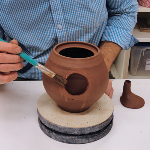 8 Trace around the spout, then cut out a hole, score and slip the spout and body, then attach and smooth the joint.