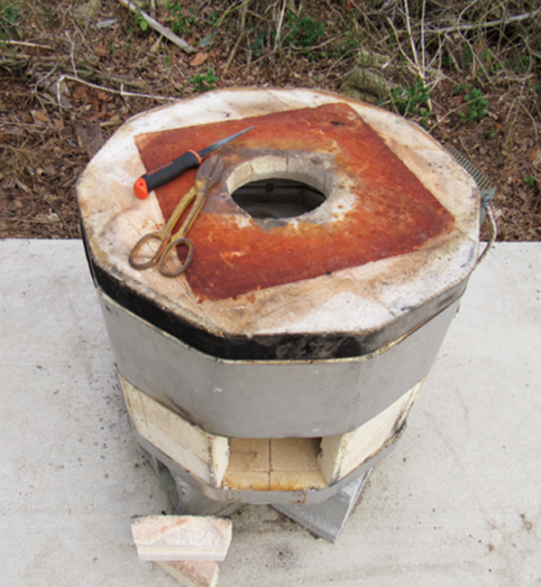 7 Cut an 8-inch-wide chimney hole in the center of the kiln lid using a wallboard saw.