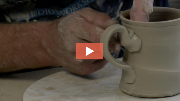 Still from video of Josh DeWeese attaching a handle to a mug.