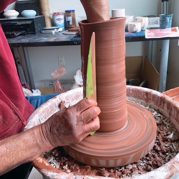 4 Smoothing the exterior before pulling the bottom clay up keeps the wall stable.