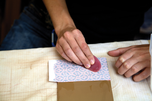 Use a rib to compress and smooth the back of the paper to help the slip transfer onto the slab.