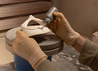 Martha Grover applies slip dots to a bisque fired piece