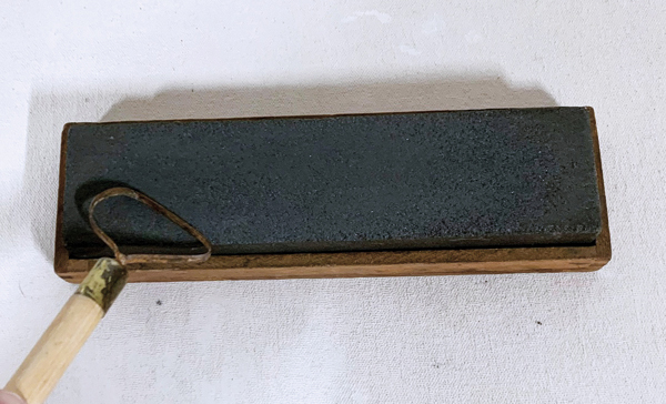 A Hold your Dolan tool at a 45° angle on the surface of the sharpening stone (grit side up). Start at the bottom corner of the stone. 