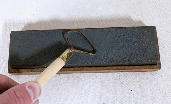 B Move the tool against the grit surface, beginning to move upward toward the middle of the stone to follow an arch motion. 