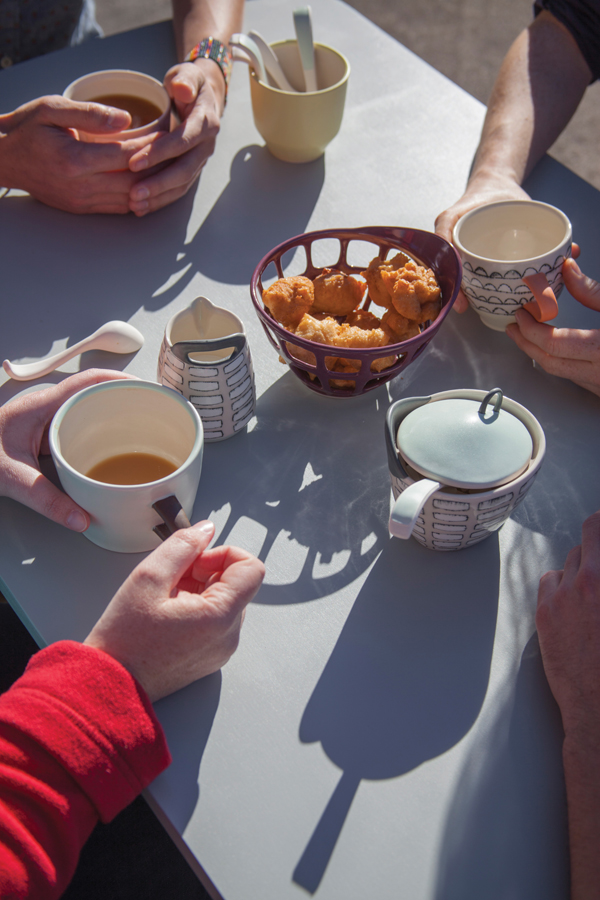 Friends enjoying loukoumades and coffee using handmade pots.