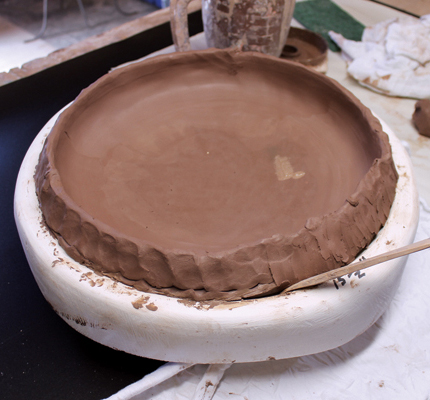 4 Put slurry on the slab rim, then add coils. Blend the seams with a wooden tool.