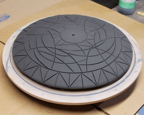 12 Apply multiple coats of black underglaze. Let dry, then paint in various colors of underglaze throughout the design.