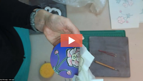 Image of Kip O'Krongly peeling off newsprint to reveal an image that was screen printed and transferred onto a piece of pottery.