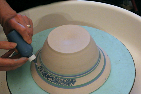 8 With the pot flipped over and centered on the wheel, repeat the design elements on the exterior of the bowl.