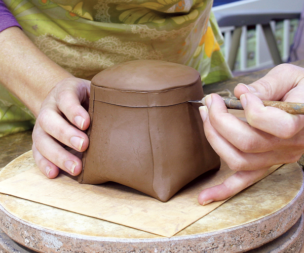 7 At the leather-hard stage, cut the lid away from the pot holding your X-Acto knife horizontal to the pot. This should be done in one motion.