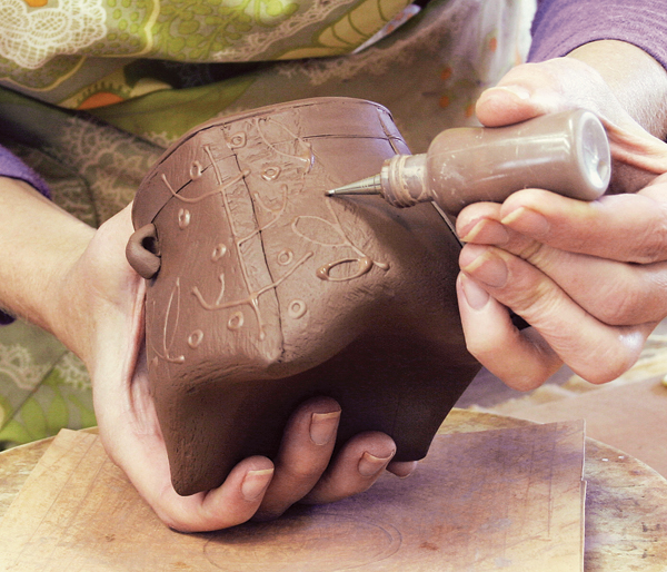 10 Use slip made from your clay body to decorate the exterior of the pot. The consistency of the slip along with the pressure used will determine the quality of line you create.