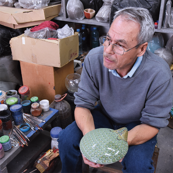 F Cortez holding a partially burnished piece to demonstrate the effect that burnishing has on the surface. 