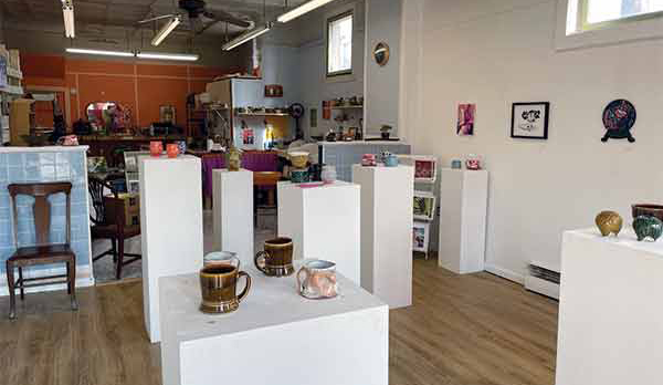 The gallery section of MadKat studios, showing mugs by Luke Doyle and Brandon Lipe on the pedestal in the foreground. Additional works by Dana Miller and Mark Tarabula can be seen in the background. 