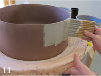 Apply a contrasting colored slip to the leather-hard bowl using a wide brush to minimize brush stroke marks.