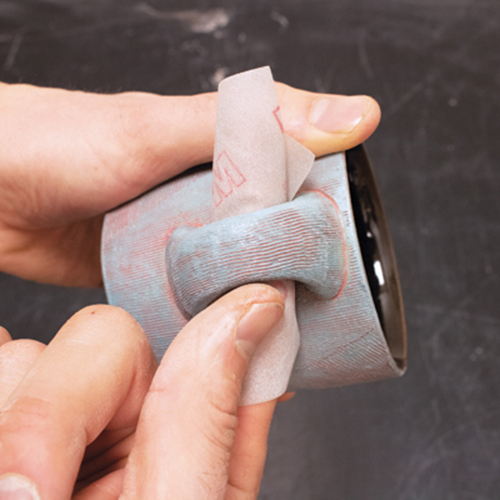 2 Sanding the surfaces of a fired mug to soften edges and enhance tactile appeal. 